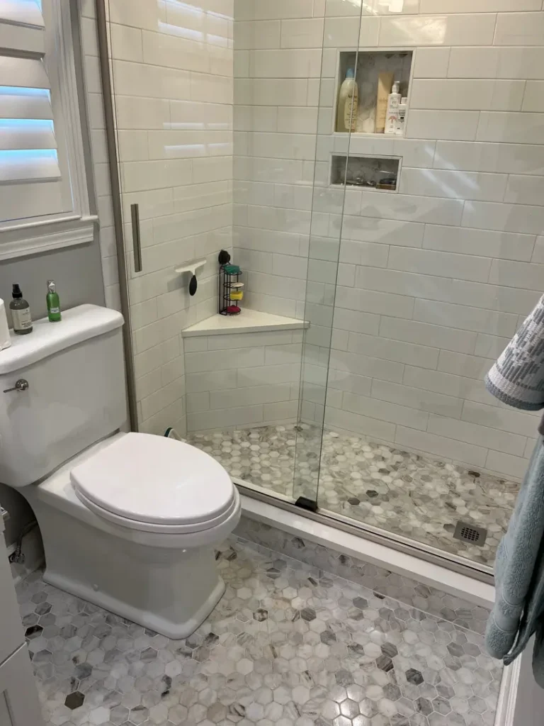 Clean bathroom with a glass shower enclosure, white toilet, and tiled floor after general cleaning in Greenville, SC.
